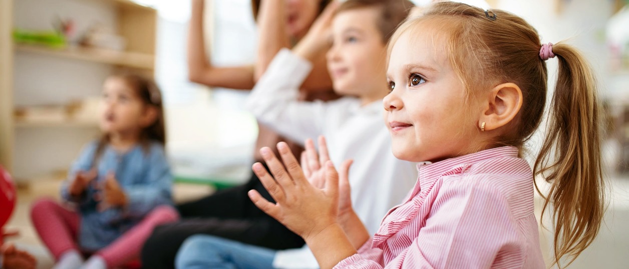 Kinder sitzen im Kreis und klatschen